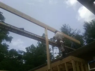 Carpenter setting a ridge beam over a new addition frame — Ice Dam Removal by Roofing Brothers in Ryderwood
