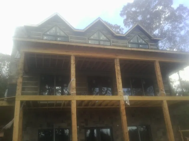 Dormers and porch framing on a large log home under construction — Roof Coating work by our crew in Ryderwood