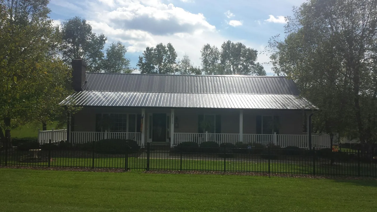 Gray metal roof on a brick ranch with a full width front porch — Gutter Guard Installation work by our crew in Ryderwood
