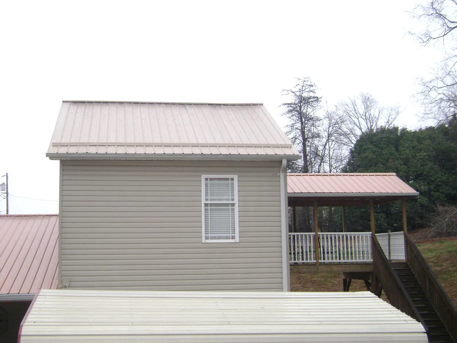 Tan metal roofs on a two story addition and attached porch, from a Roof Replacement job in Ryderwood