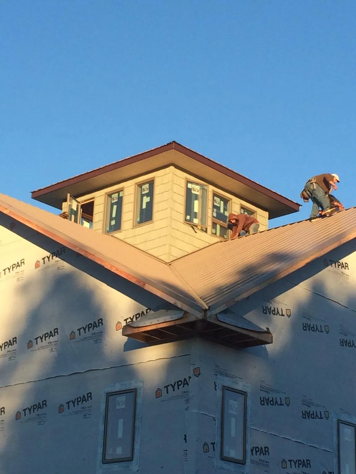 Roofers working around a rooftop cupola on a new metal roof at sunset — Roof Waterproofing in Ryderwood by Roofing Brothers